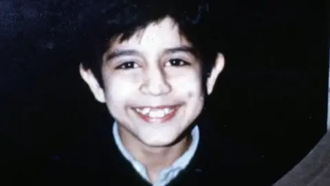 A handout of eight-year-old Vishal Mehrotra’s who disappeared from Putney in 1981. Vishal is smiling to camera and is wearing a dark jumper and white shirt.