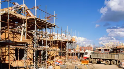 Getty Images A general view image of a housing estate that is partially built. The structures have scaffolding all over them and a truck is parked up nearby. 