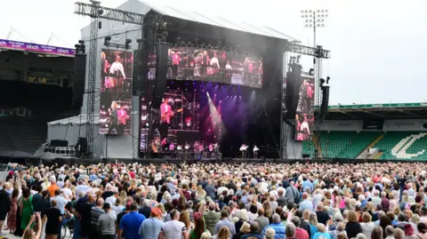 Northampton Saints Rod Stewart on stage in Northampton with crowds of people watching.