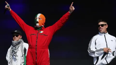  Kneecap's Mo Chara, DJ Provai, and Moglai Bap stand on stage at Glastonbury