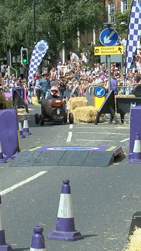 A soapbox car driving through Newbury town centre.