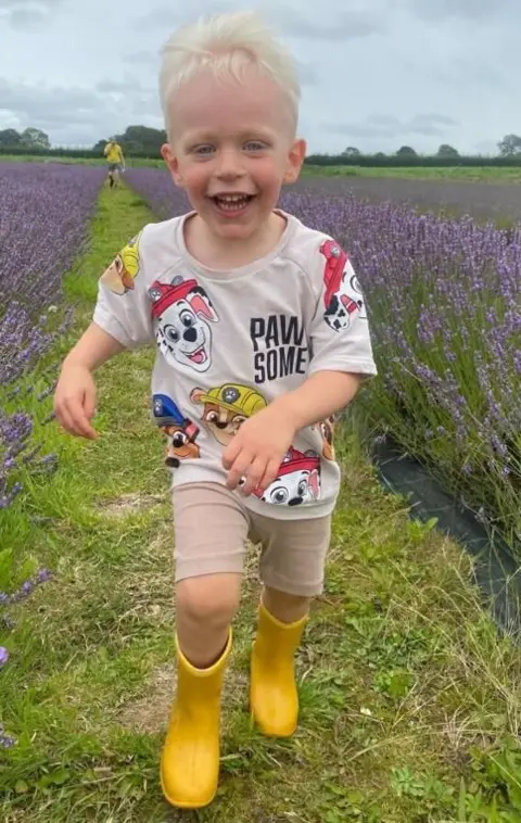 Family Handout Oscar in a field wearing yellow wellies and a Paw Patrol t-shirt