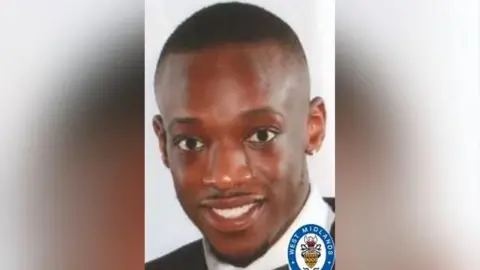 A man with short dark hair and a black collared top