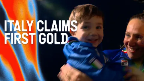 Francesca Lollobrigida celebrates winning gold in the women's 3000m speed skating with her son at the 2026 Winter Olympics