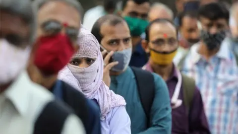 Reuters People wearing protective masks wait in line to board a bus amidst the spread of the coronavirus disease (COVID-19) in Mumbai, India, October, 6, 2020