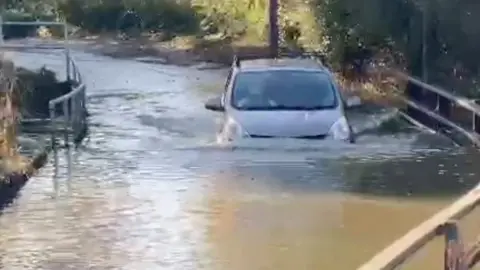 Car driving through deep floodwater.