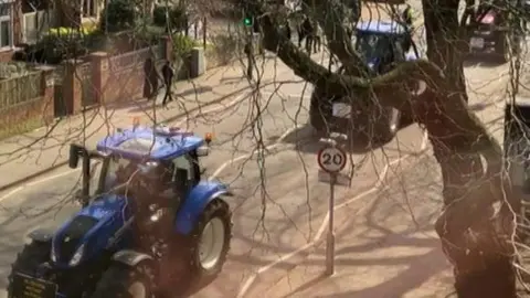 BBC Tractors drive through Summertown, with banners affixed to their bumpers