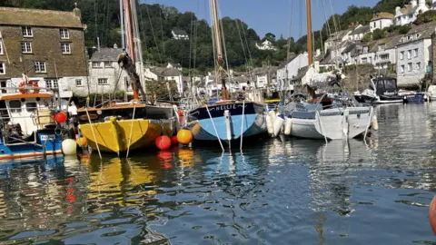 Three traditional wooden boats sit alongside each other, one is yellow, the next blue and the final one white