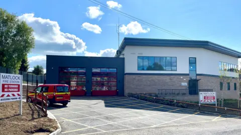 An image of Matlock new fire station with a red fire service van parked at the front