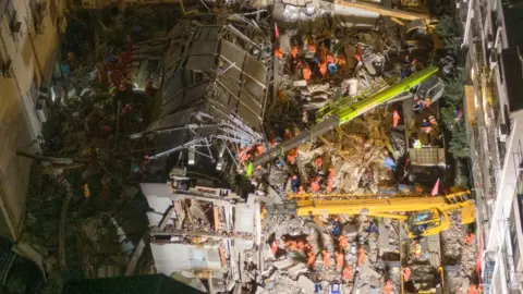 Getty Images Aerial view of rescuers searching for trapped people in the debris of a collapsed hotel on July 13, 2021 in Suzhou