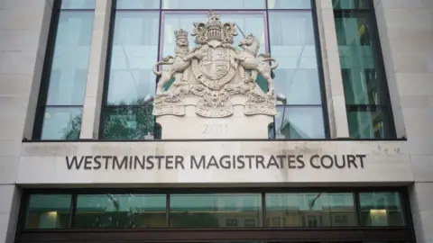 A general view of the entrance to Westminster Magistrates Court. The name of the court is written on the front of the building above an entrance. The HM Courts and Tribunal Service emblem rests above the court name.