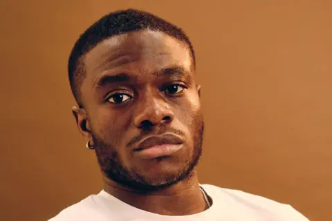 A photo portrait of V.I.C. He wears a white t-shirt.