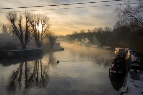 Jemma Ridley Seemingly Beautiful - narrowboats on a river lined with trees, with mist in the air
