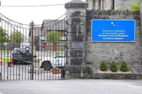 PA A car wrapped in black plastic and a garda car at the scene at Renmore Barracks in County Galway, after an army chaplain was stabbed