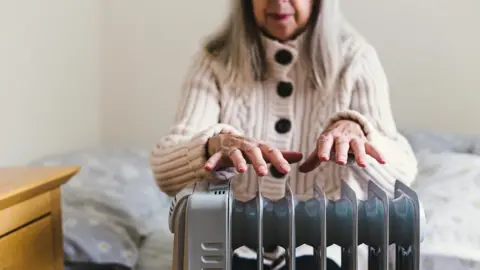 Getty Images Woman warming her hands on a radiator