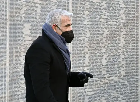 Hans Punz / AFP Israel's Foreign Minister Yair Lapid visits the Wall of Names Memorial in the Ostarrichi Park in Vienna, Austria on 27 January 2022