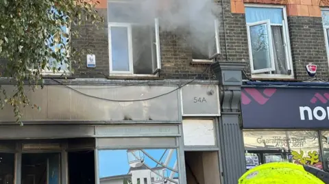 Essex Fire and Rescue Service Burnt out shop front with smoke coming from two upper storey windows. 