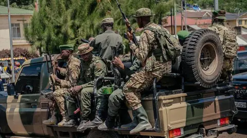 Soldiers in uniform, with guns, atop a pickup truck