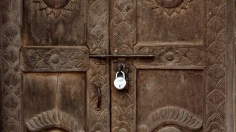 An ornate wooden door is locked and bolted shut