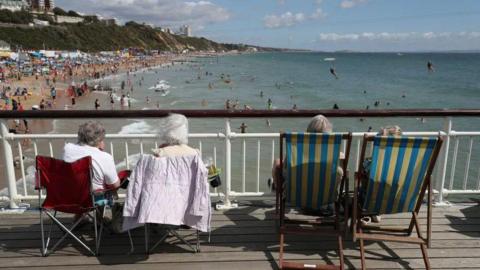 Four people sitting on deck chairs overlooking Bournemouth beach