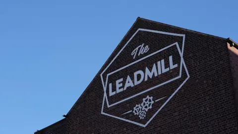 A painted sign on the side of a building which reads 'The Leadmill'.