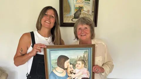 Sophie Cook and Teresa Cook stood holding a painting