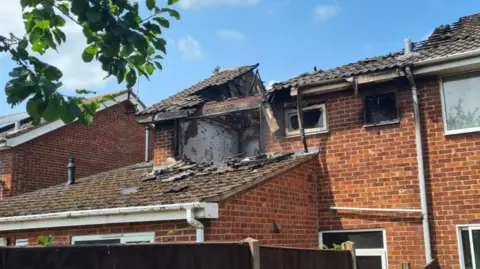 A house with a collapsed and fire-damaged roof