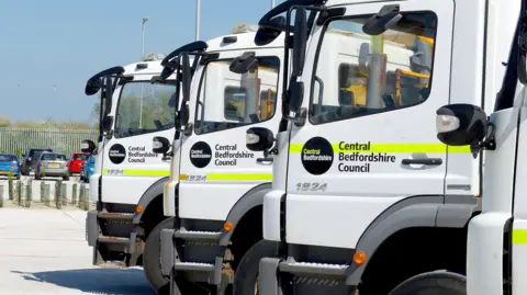 Central Bedfordshire Council Three parked gritting lorries on a sunny day with Central Bedfordshire branding on the doors.
