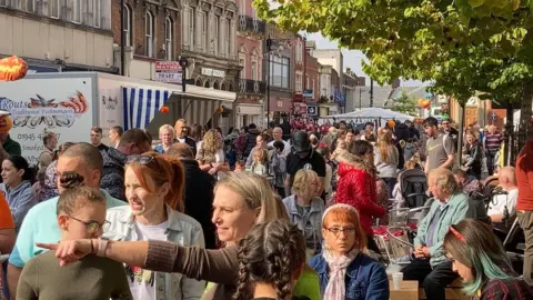 South Holland District Council Crowds of people can be seen in Spalding town centre, with some sitting down to enjoy food and drink and others taking in the sights. 