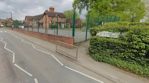 Google A section of the A4111, going from roughly the top left to near the bottom right of the image. Bushes and trees are on the right of the photo and a school is in the distance on the left.