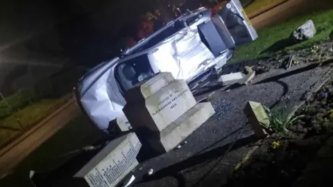 A car on its side near the toppled war memorial