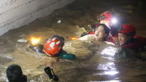 KIM HEE-CHUL/EPA Firefighters and military officials rescue one of the missing residents