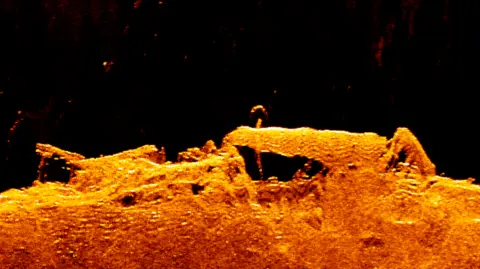 Sonar imagery of the wreck at the bottom of the harbour. It is an orange outline of the top of the vessel, with possible machinery on the deck.