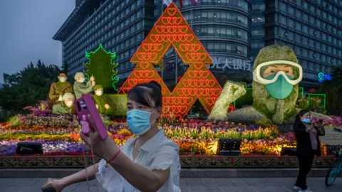 Getty Images A woman takes a selfie in front of a display for healthcare workers