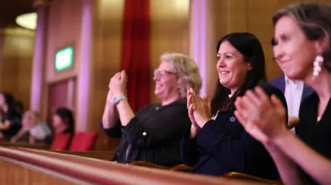 LCRCA Lisa Nandy smiling and applauding a young people's performance at the Liverpool Philharmonic.