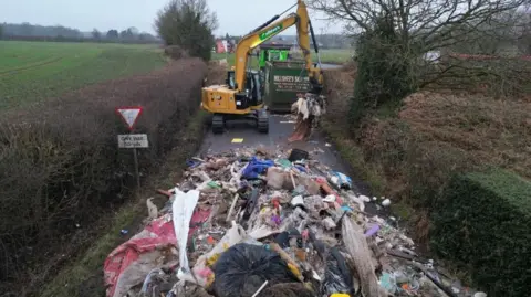 Phil Barnett/PA Wire Contractors work to remove a pile of waste from Watery Lane, on the outskirts of Lichfield in Staffordshire.