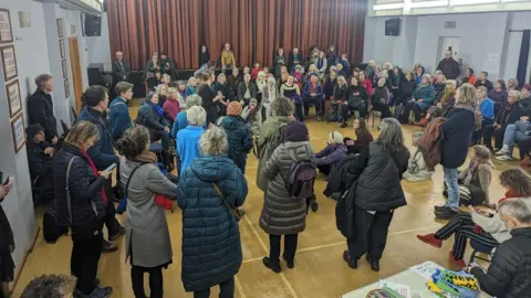 Duncan Appleby A climate choir gathered to rehearse inside a large room