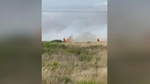 Andrew Lee Fire crews in a field in Romney Marsh using high pressure hoses to put out flames