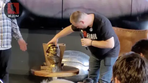 BBC Video screen grab of Takarsky looking at figure wearing helmet