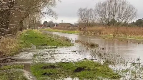 RUSSELL BIGGS Water running over the bank of the Gaywood River in King's Lynn