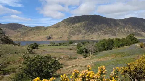 General view of the countryside at Rannerdale in the Lake District, Cumbria, with Crummock Water and mountains in the distance.
