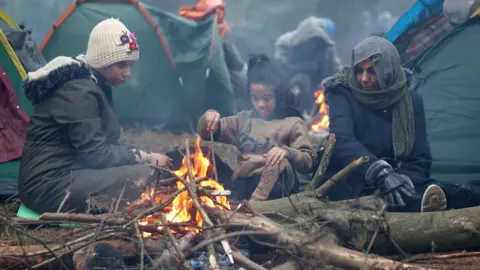 Reuters Migrants gather near a fire on the Belarusian-Polish border