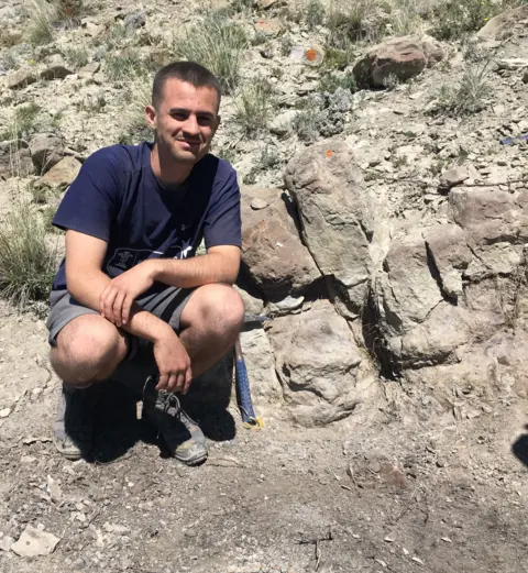 Ewan Bodenham Ewan Bodenham crouches next to rocks during a dig.