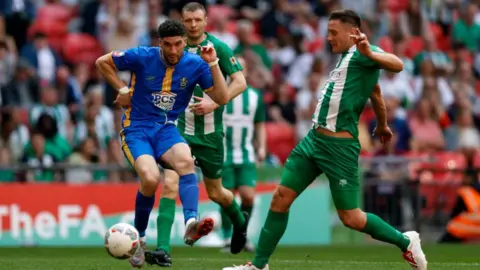 PA Media Green and blue players fight for the ball