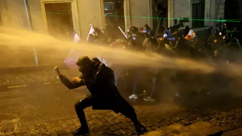  Police officers use water cannons to desperse demonstrators during clashes as part of a protest outside the Parliament building against the government's decision to delay European Union membership talks amid a post-election crisis, in Tbilisi on December 1, 2024.