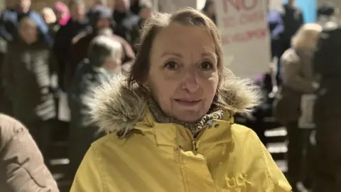 A woman with blonde hair and a yellow coat