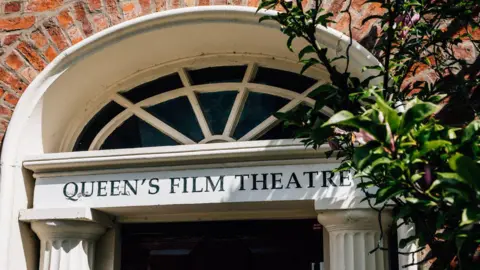 Ivan Ewart A close up photo of the top of the door at QFT. Queen's Film Theatre is written in capital letters on the top of a white door frame.