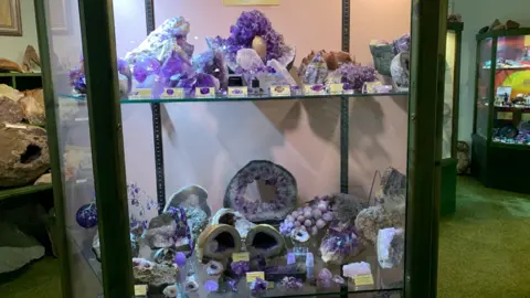 A display cabinet full of purple gem stones