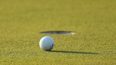 A generic shot of a golf ball beside a hole