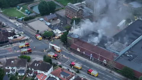 Eddie Mitchell Several fire engines surround a smoking supermarket. 